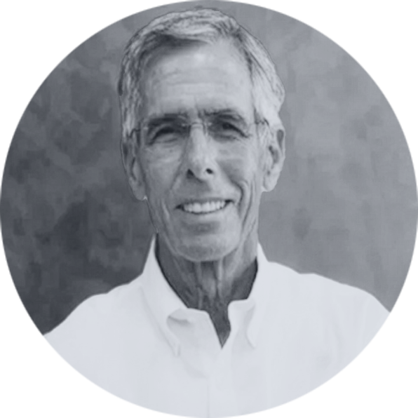 Smiling Older Man Grayscale Professional Headshot Grayscale headshot of a smiling older man with glasses and short gray hair, wearing a white collared shirt in a circular fra…