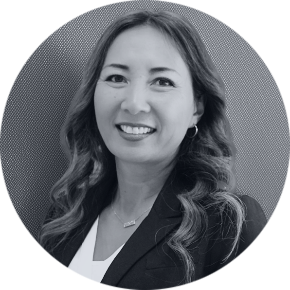 Professional Woman Smiling Portrait Black and White Smiling Asian woman with long wavy hair, wearing a blazer and necklace, in a black and white circular portrait.
