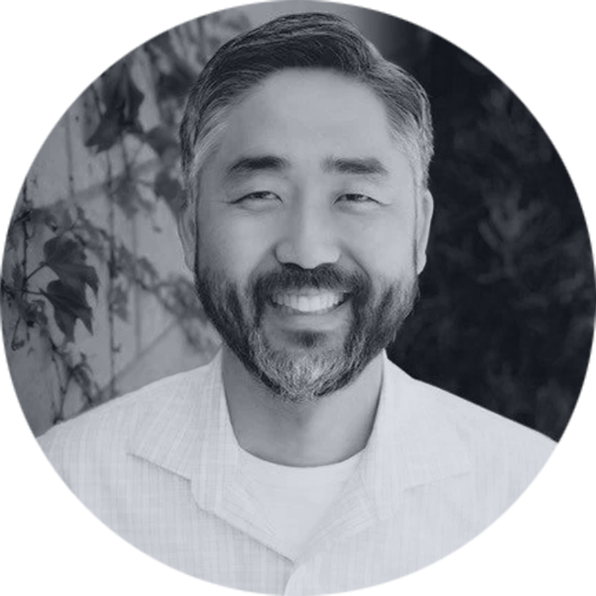 Professional Portrait: Smiling Man with Beard and Grey Hair Smiling Asian man with a salt-and-pepper beard and short grey hair, wearing a light collared shirt, against a leafy backgrou…